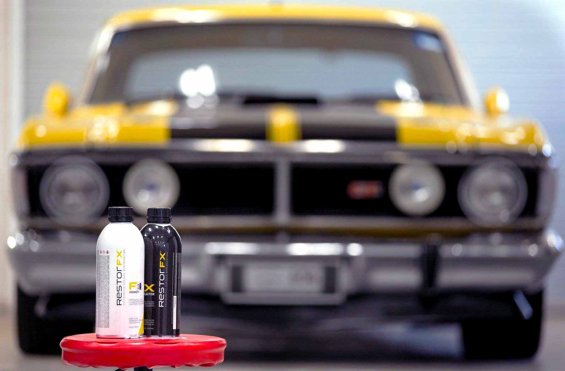 Frascos de produtos de restauração <span  class='notranslate'>RestorFX</span> F e X com um carro esportivo antigo amarelo brilhante ao fundo