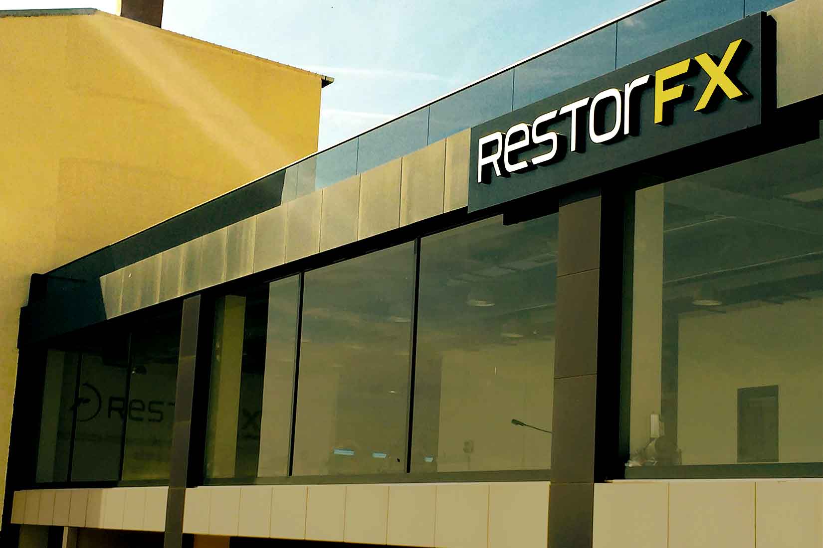 Fachada frontal de RestorFX Turquía con rayos de luz brillando en su señalización moderna y elegante y ventanas de vidrio