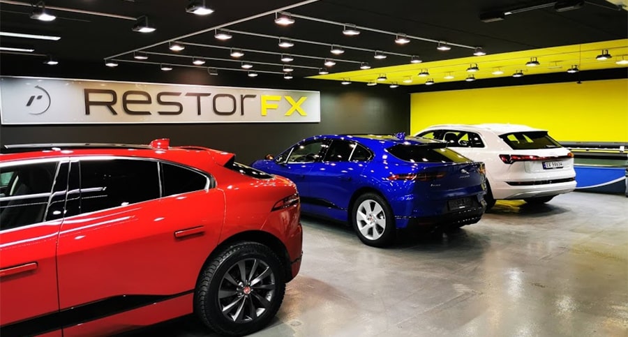 Vibrant RestorFX Center work area with yellow accent walls, bright accent lights and red, blue and white sedans