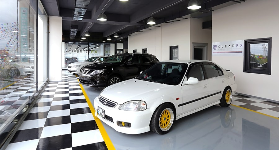 Beautiful, bright showroom inside a RestorFX Center with a row of shiny cars, tall glass windows and office spaces