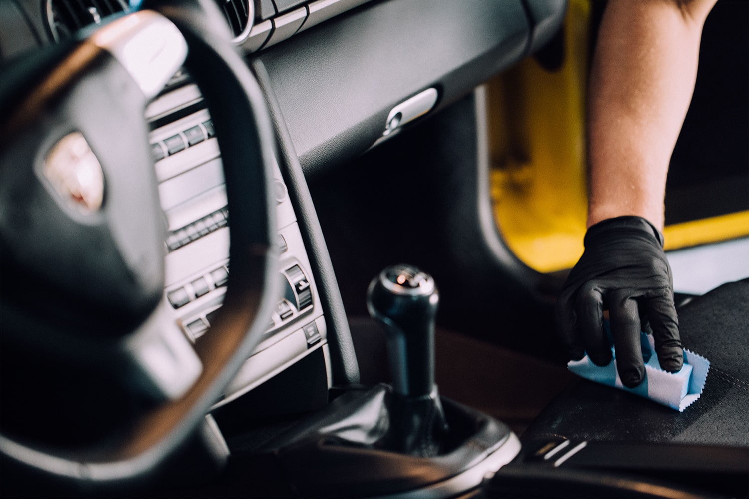 Un technicien RestorFX protégeant la console en cuir d'une voiture de sport jaune avec le produit <span  class='notranslate'><span  class='notranslate'>ClearFX</span> Interior</span>