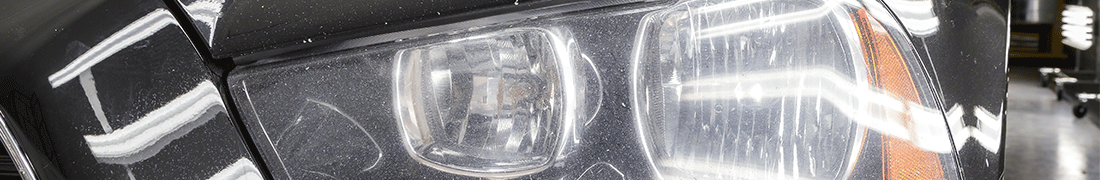 Cloudy, blemished, dull and transluscent left headlight of a black sedan before FX Headlight restoration treatment