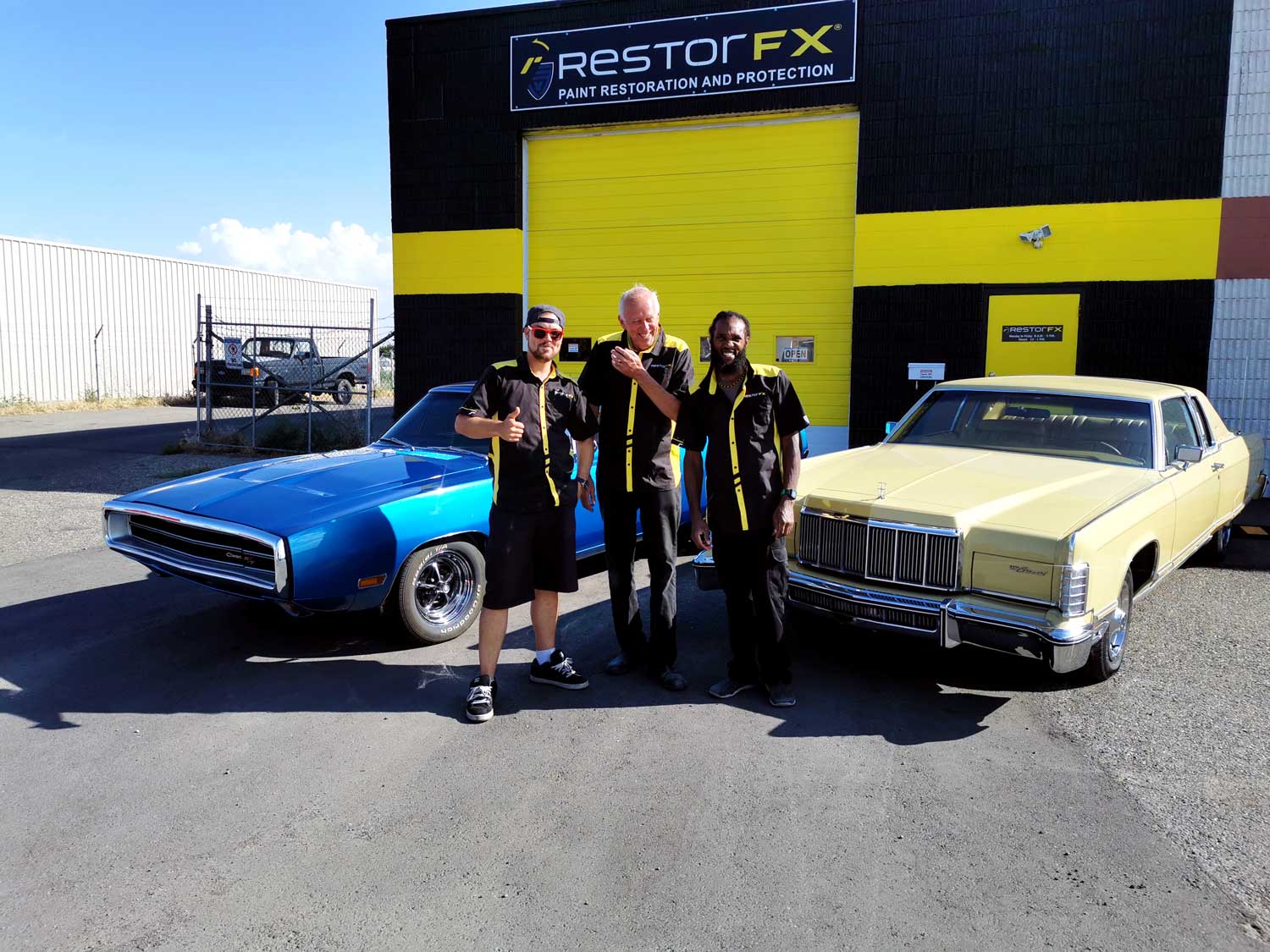 RestorFX Lethbridge team in front of the Center with blue and off-white classic cars in midday sun