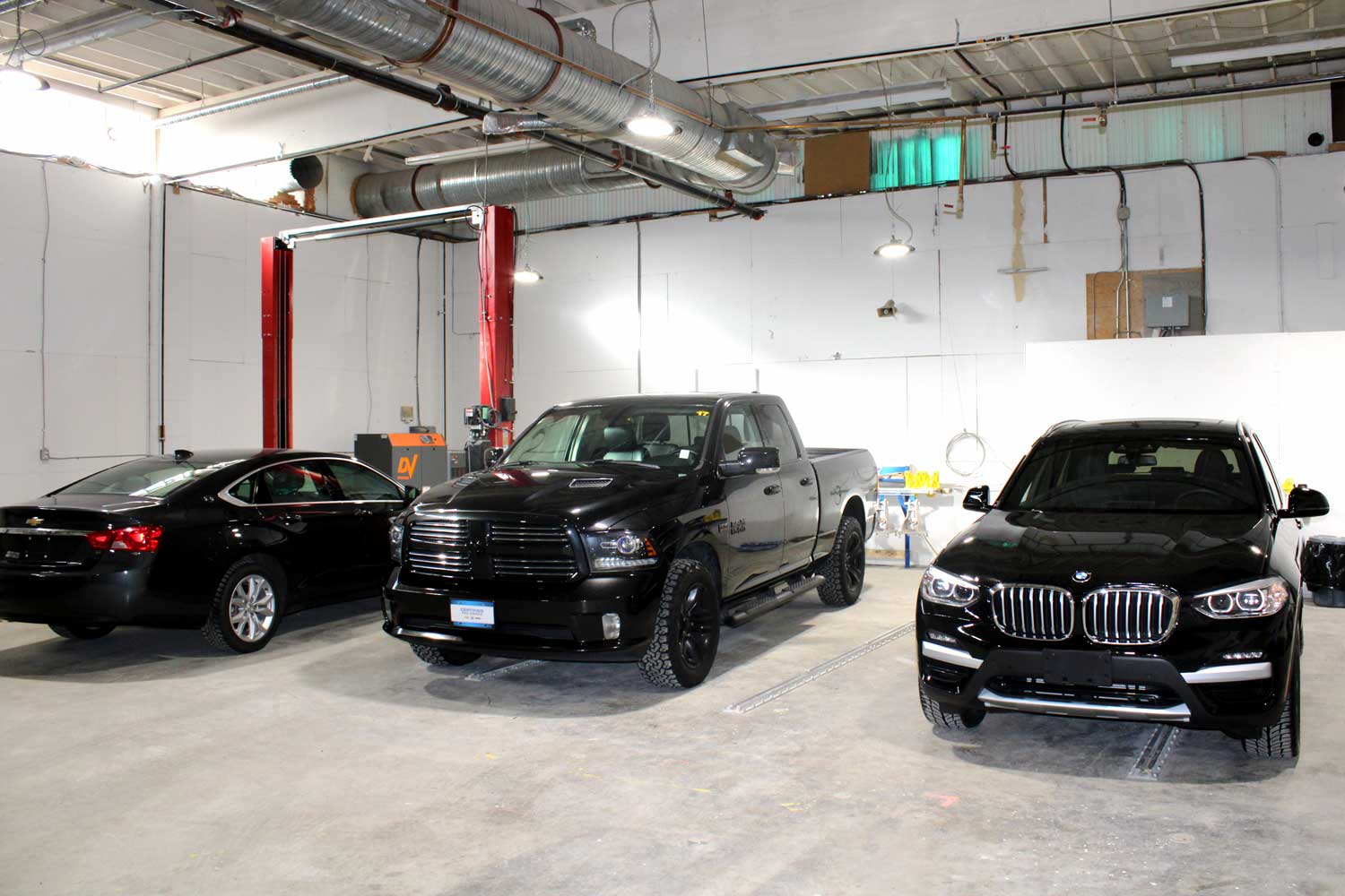 Three shiny black vehicles at different stages of paint restoration in RestorFX Richmond shop area
