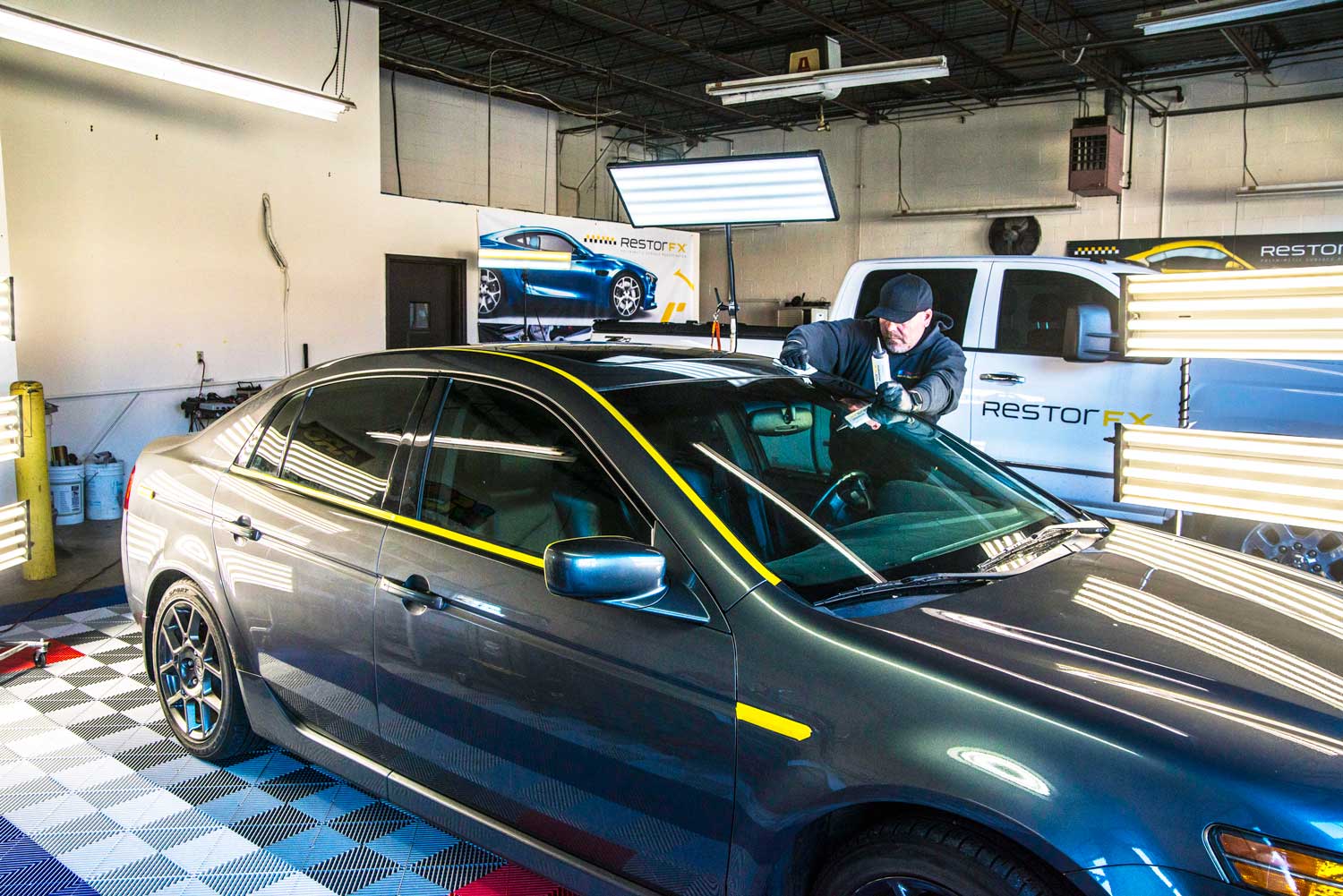 Technician restoring vehicle in highly illuminated shop area at the RestorFX Pittsburgh center