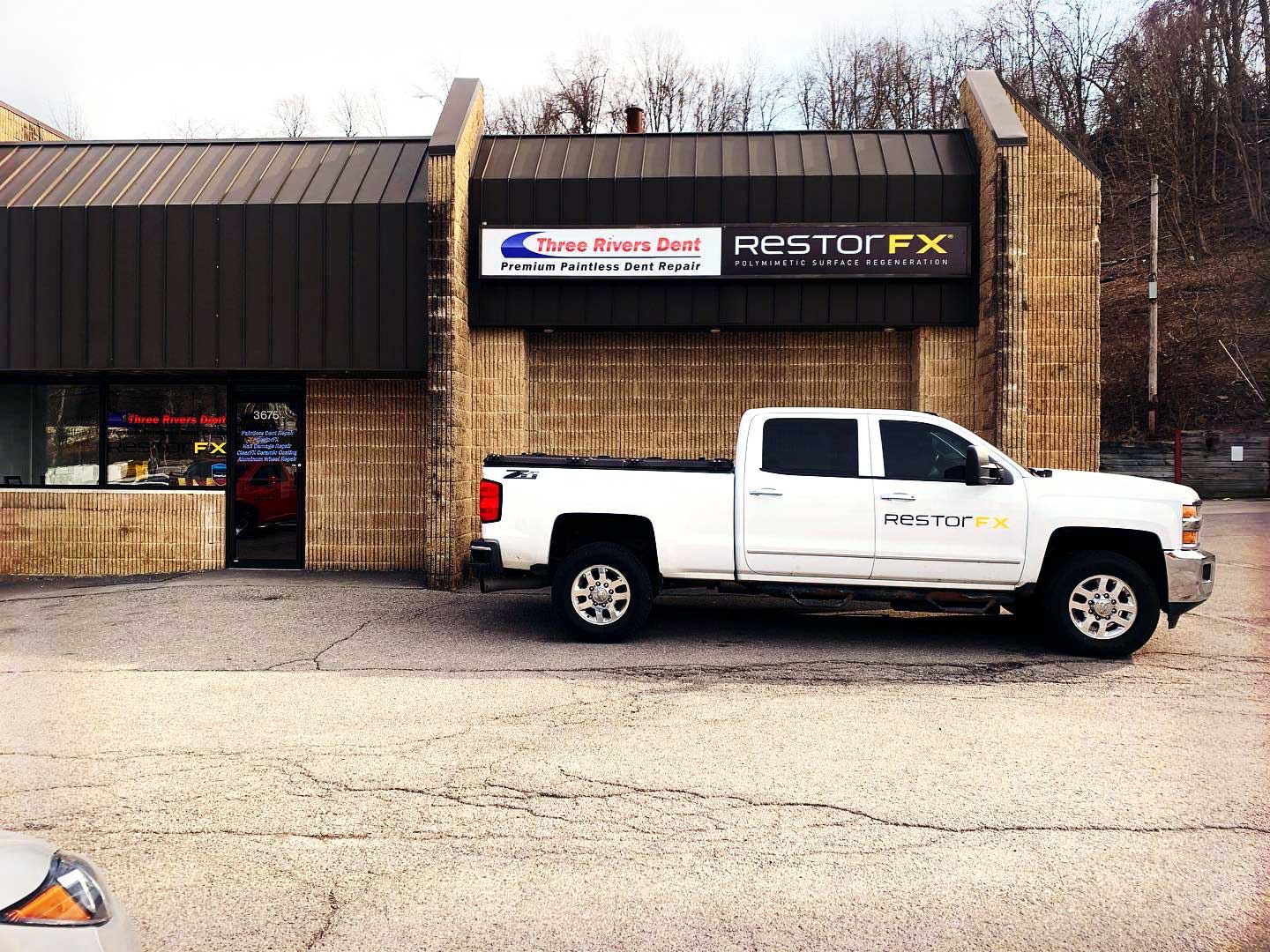 Branded white truck at RestorFX Pittsburgh storefront with brickwalls, signage and glass panels
