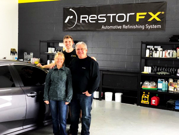 RestorFX Gainesville team at branded shop area next to shiny Honda after paint restoration training