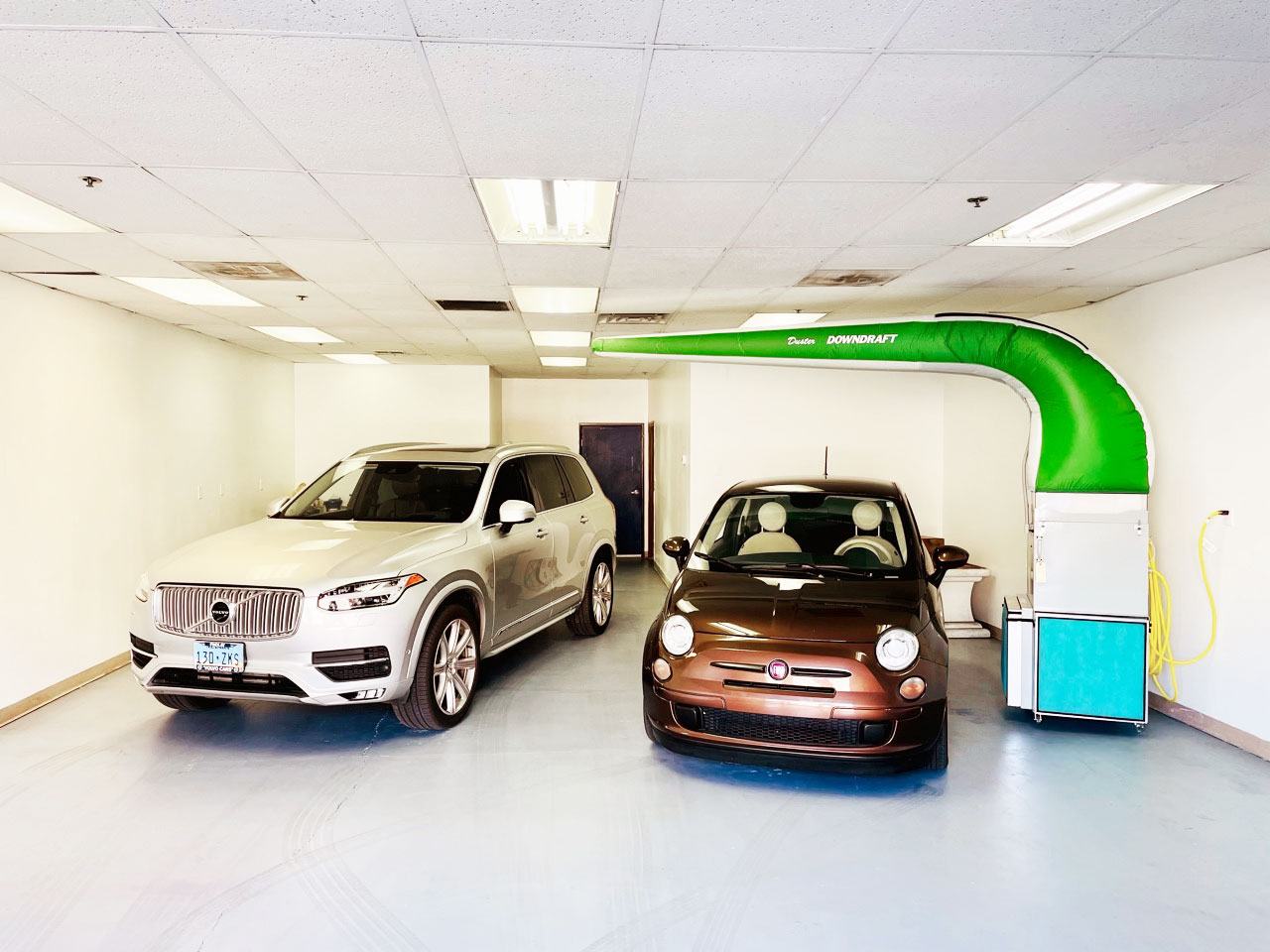 A shiny Volvo and a Fiat in brightly illuminated showroom at the RestorFX Las Vegas center
