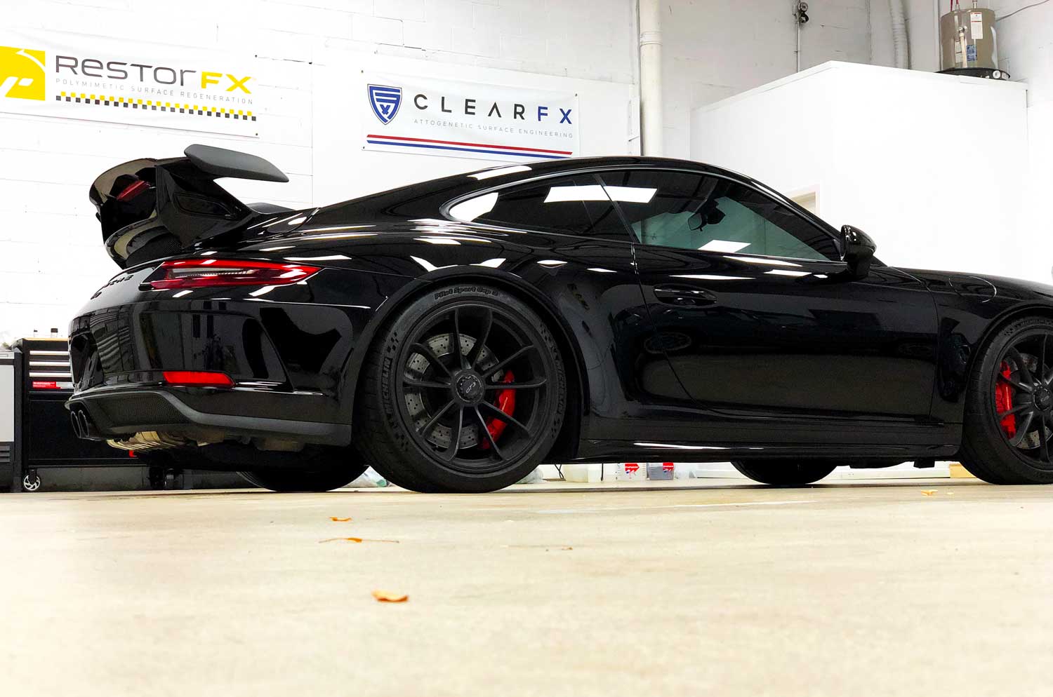 Shiny black Porsche after RestorFX application at brightly lit RestorFX Mississauga shop area