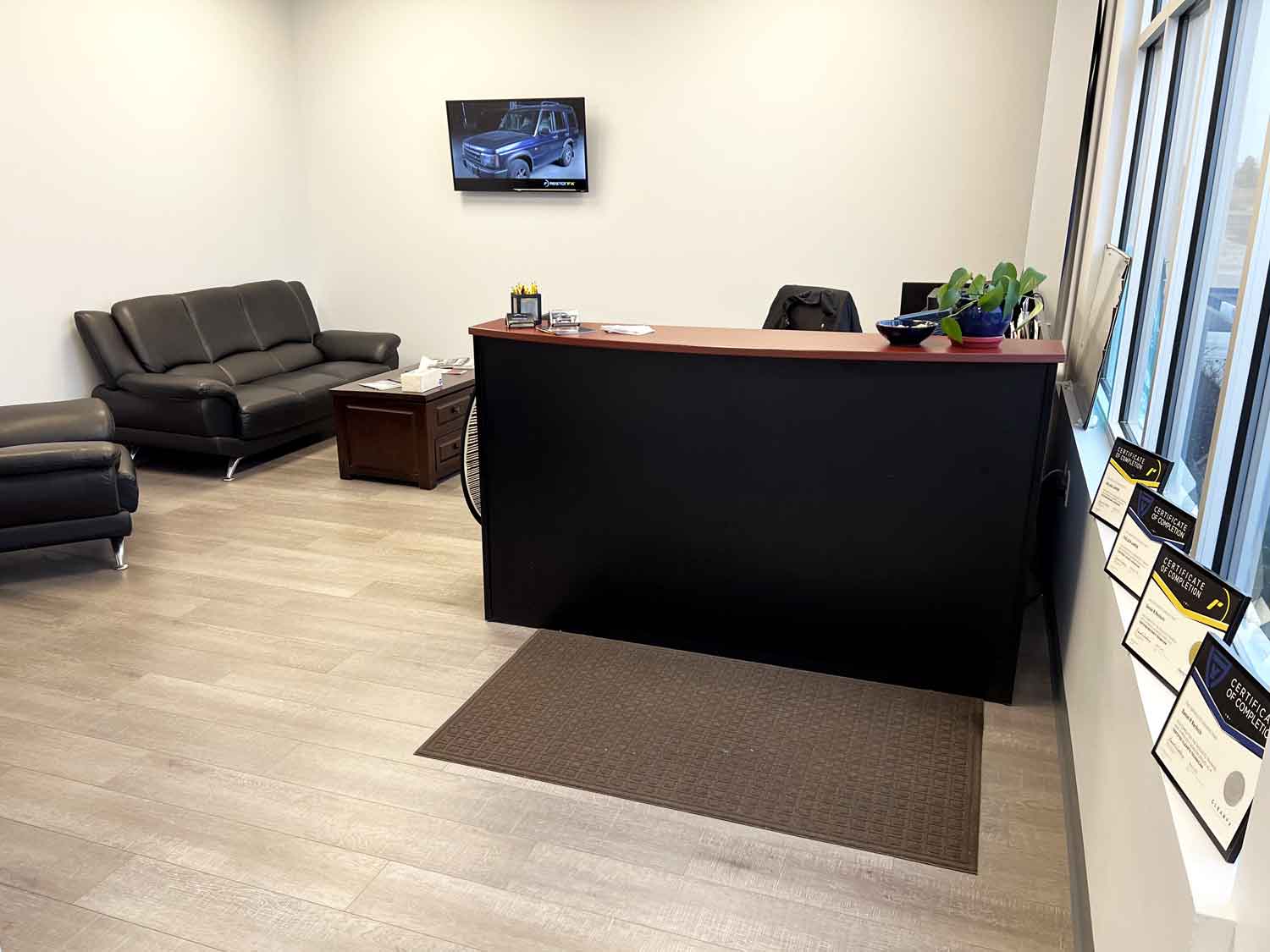 RestorFX Rochester lobby area with RestorFX and ClearFX certificates displayed, couch, mounted TV and front desk