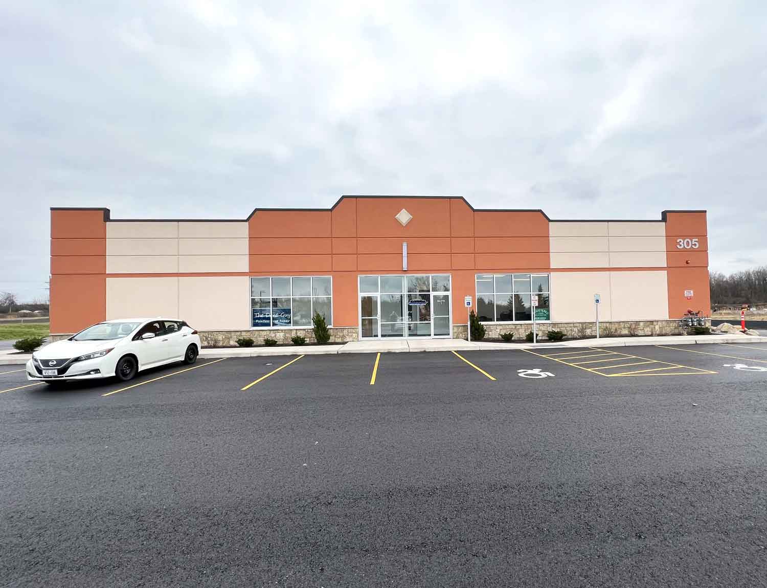 RestorFX Rochester building store front in beige and orange colors with white car parked in front