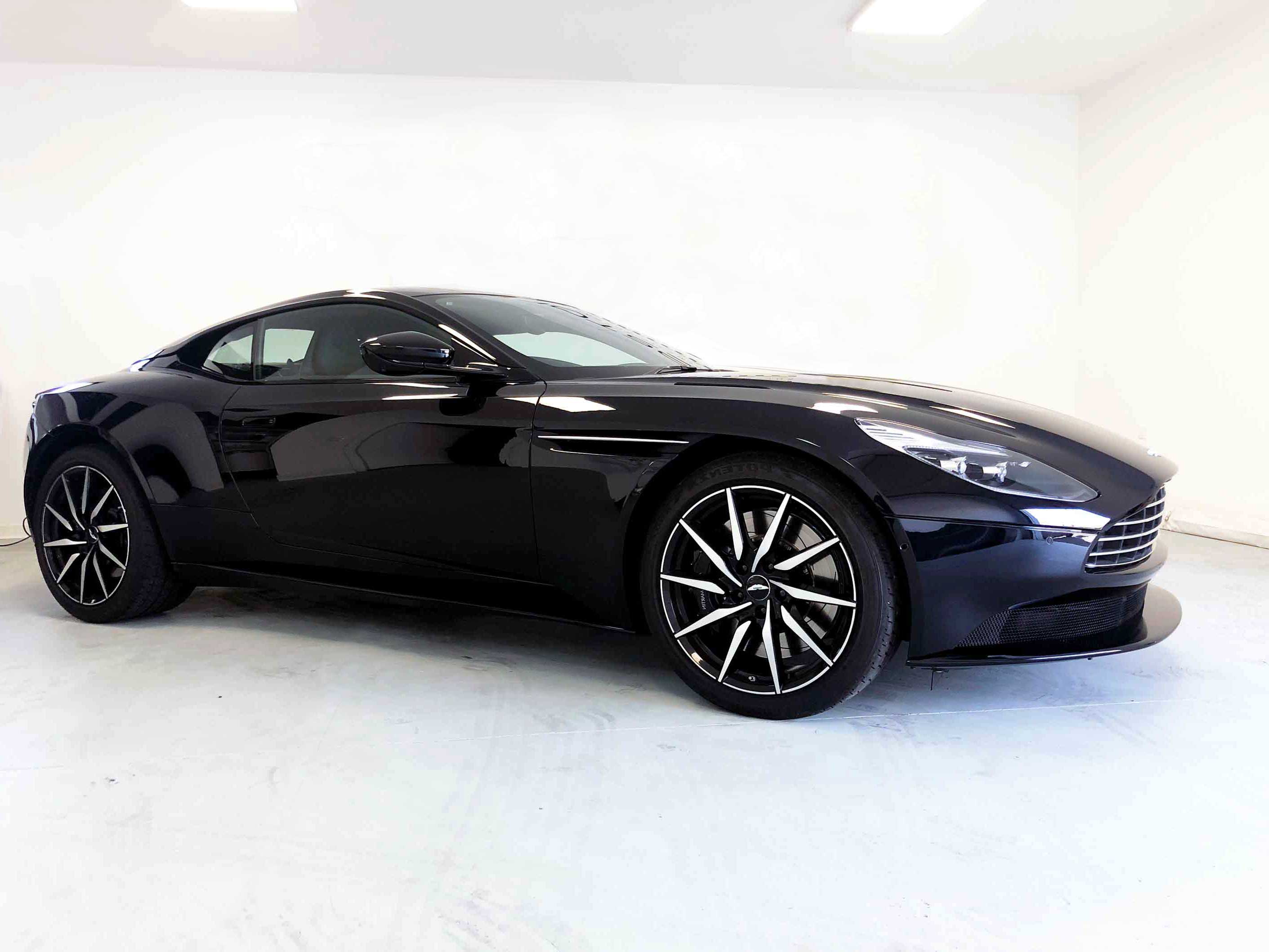 Side-view of fully restored, luxurious black car in brightly lit and clear showroom space