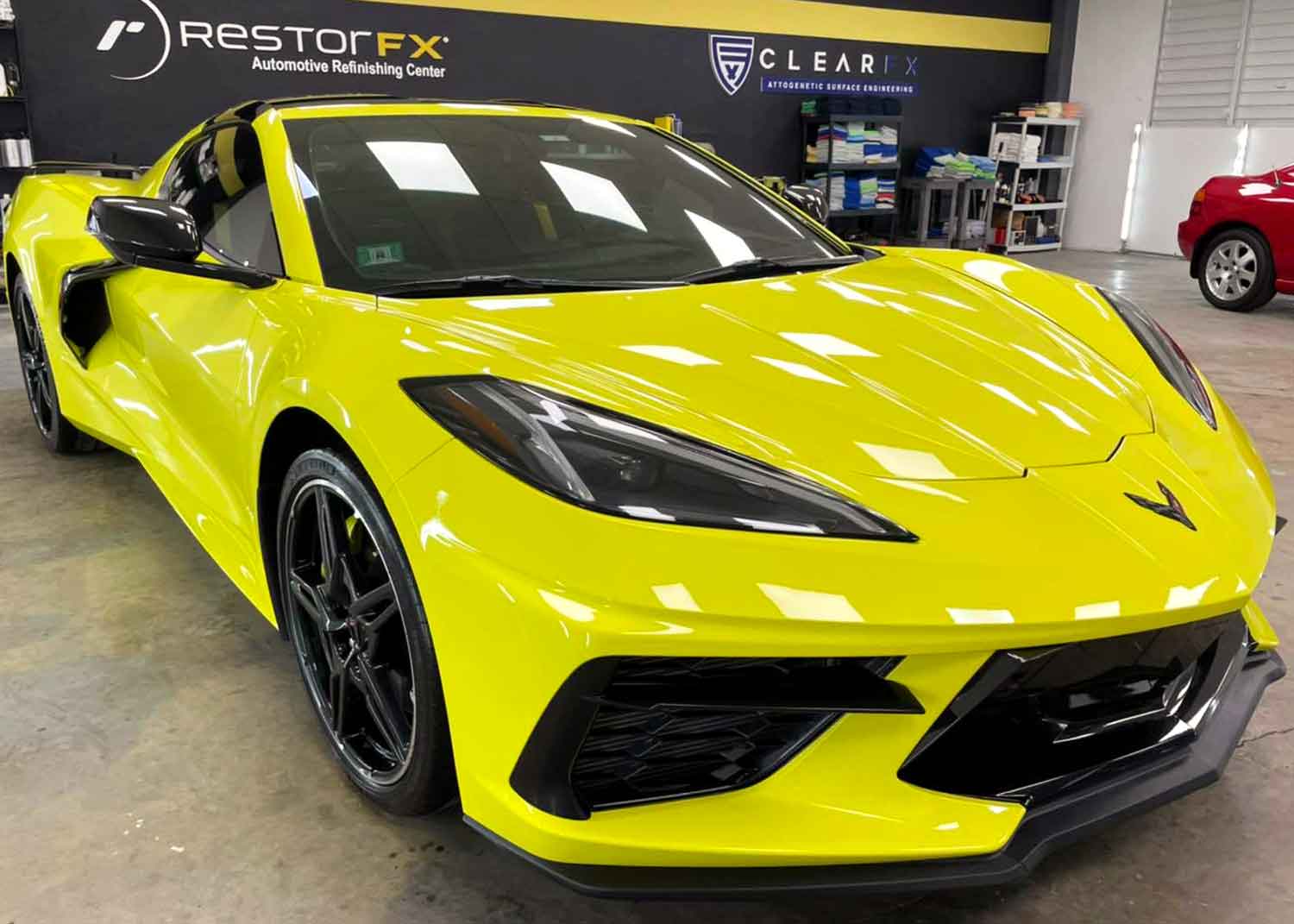 Yellow Corvette parked inside RestorFX Puerto Rico center with branded wall in the background