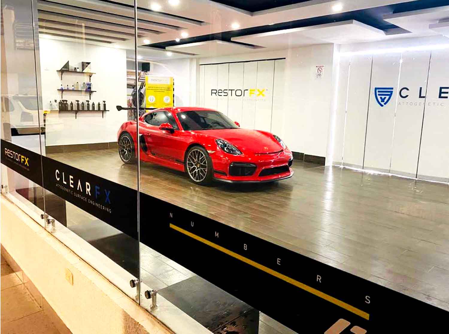 Red Porsche parked inside a well lit RestorFX Ambit center with branded walls