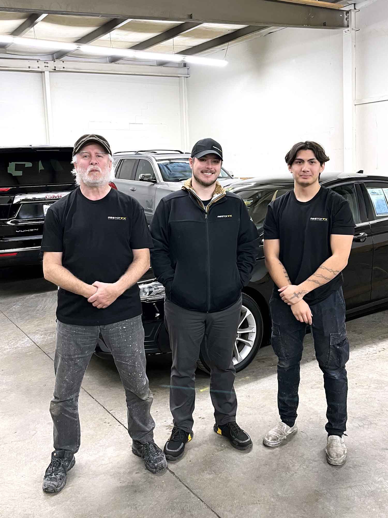 RestorFX Renton team inside the shop area with white walls and cars parked in the back