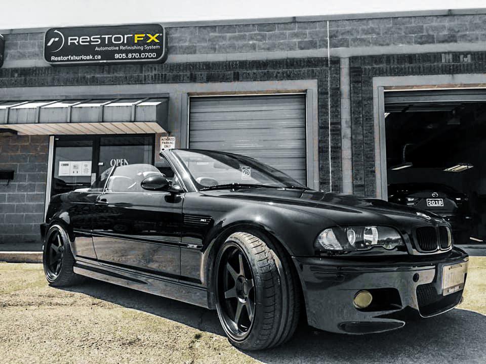 Shiny black BMW convertible at RestorFX Burlington storefront with brick facade and branded signage