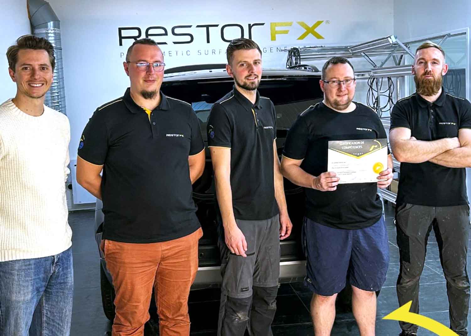 RestorFX La Rochelle team inside the brightly lit shop area with RestorFX sign on white wall and a black SUV  in the background