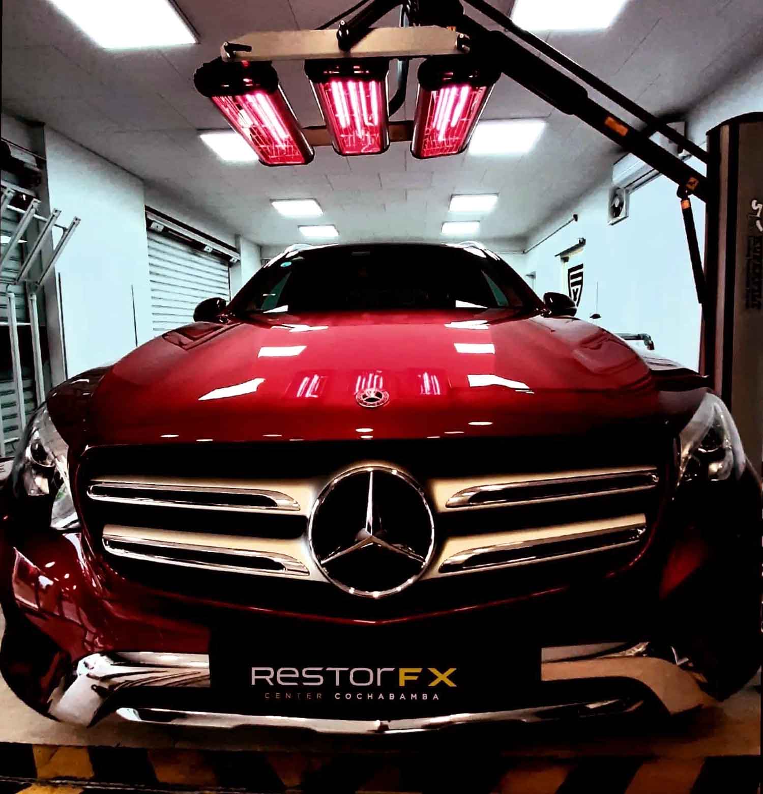 Bright red Mercedes SUV parked under infrared lamps inside RestorFX Cochabamba center
