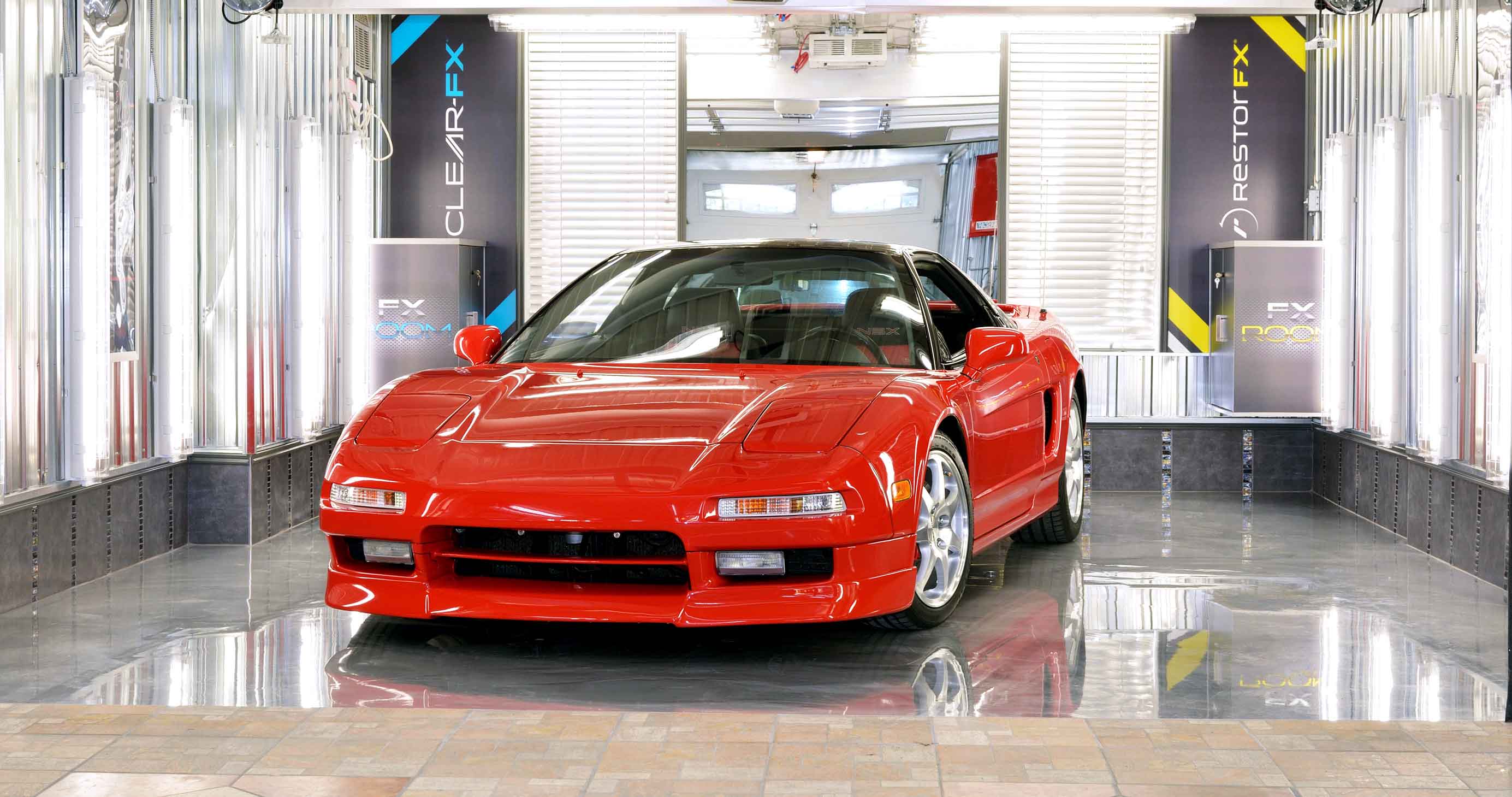 Shiny red Ferrari in brightly lit shop area at RestorFX Quebec with branded signage in the back