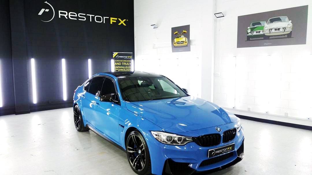 Shiny blue BMW at brightly lit RestorFX Rotherham shop area with brick walls and branded signage