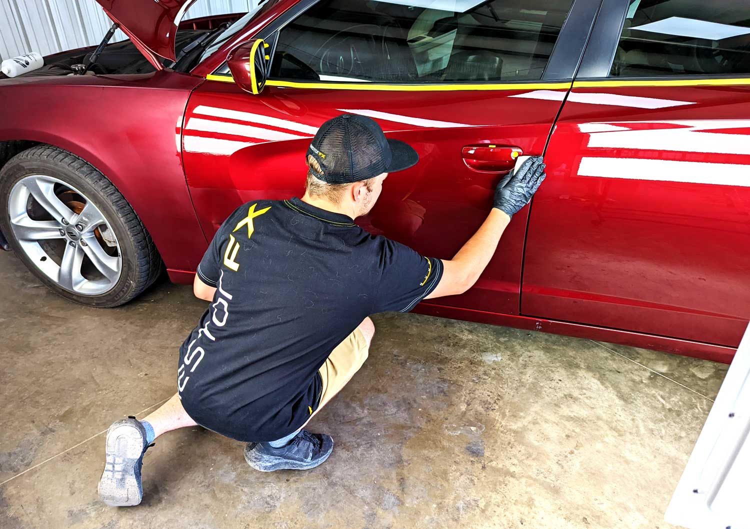 RestorFX technician applies restorative product onto red vehicle's brightly lit shiny door
