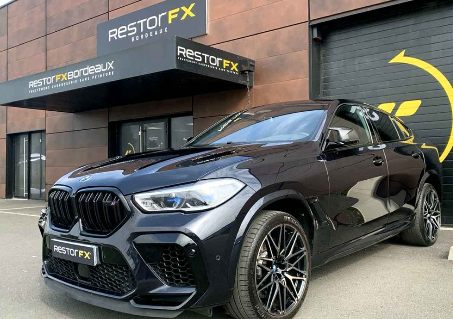 Black BMW SUV parked in front of the RestorFX Bordeaux storefront