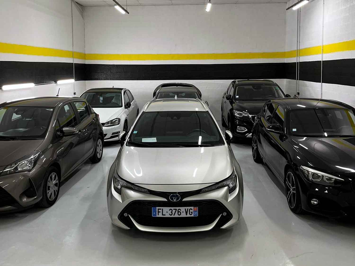 Cars parked in two rows inside the shop area of RestorFX Beauvais center