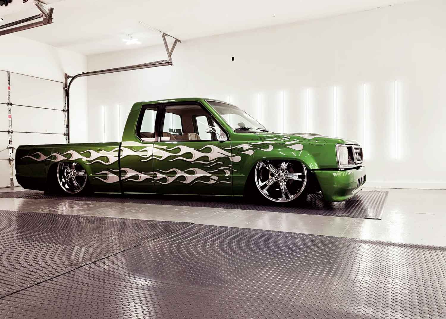 Close up of a green low rider parked in a well lit RestorFX West Niagara shop