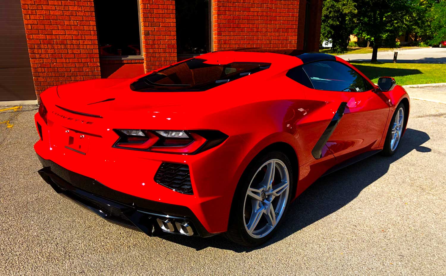 Shiny red Corvette after ClearFX application at RestorFX Mississauga storefront with bricked walls