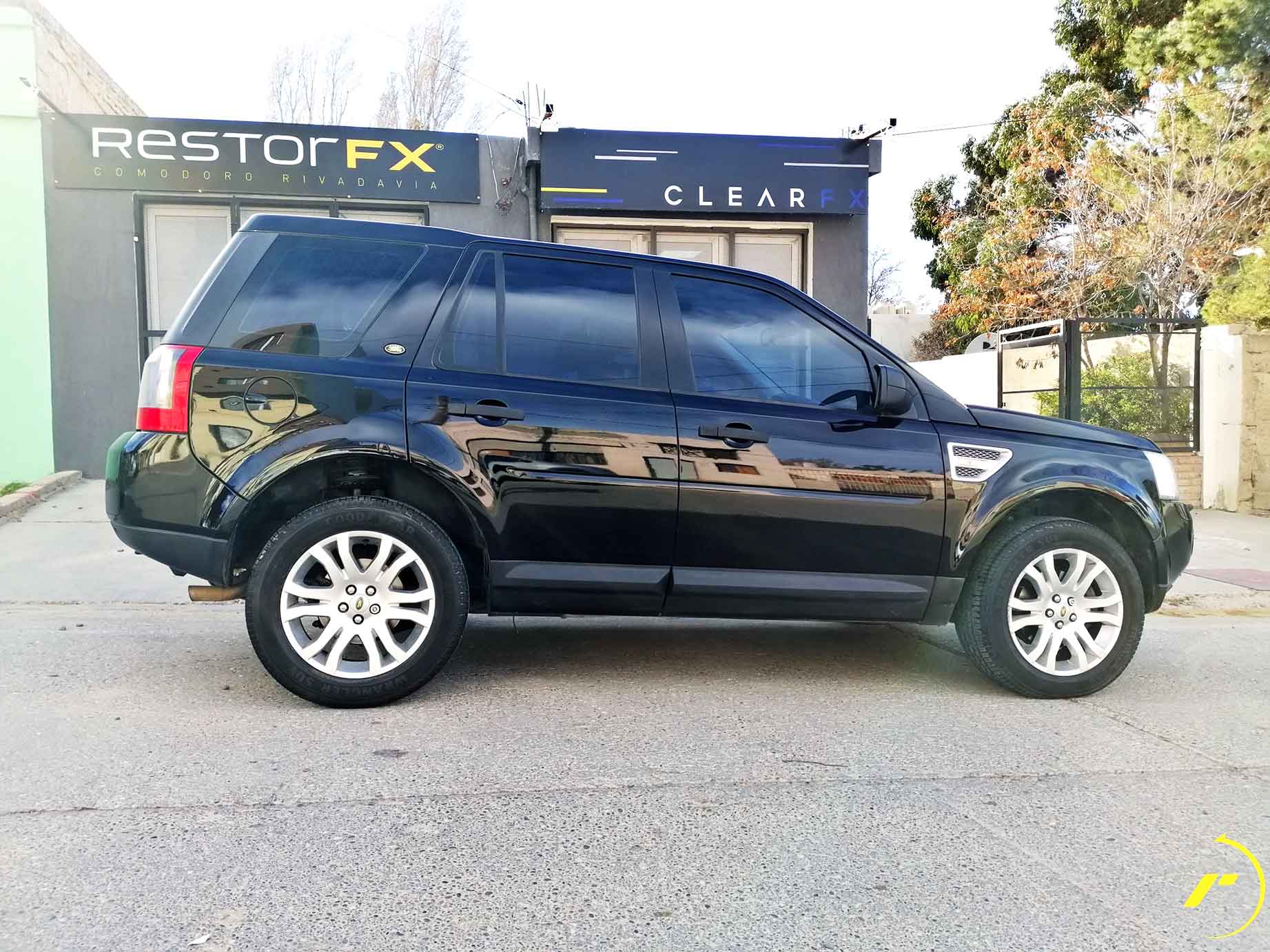 Black vehicle at RestorFX Comodoro storefront with glass panels, branded signage and grey façade