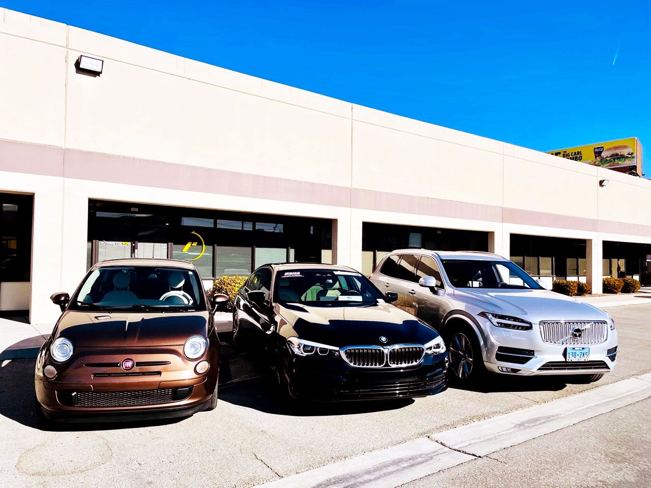 Shiny Fiat, BMW and Volvo parked in the storefront of the RestorFX Las Vegas on sunny blue-sky day