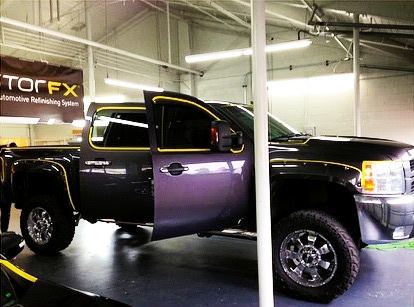 Restored purple truck at illuminated shop area of RestorFX Seattle with branded signage in the back