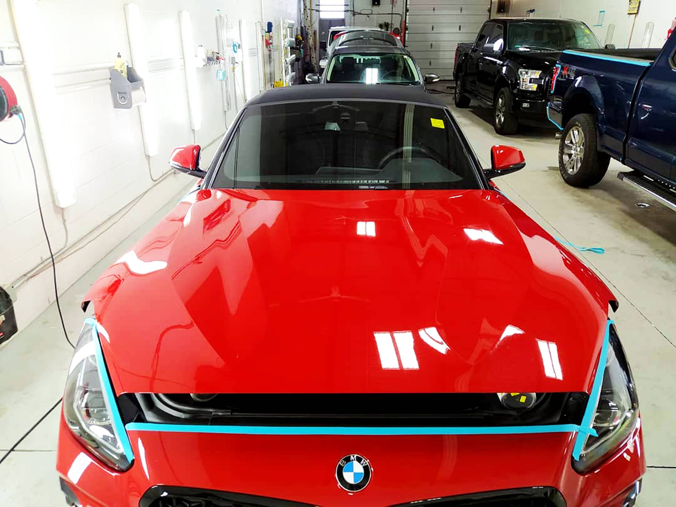 Shiny red BMW convertible being prepared for paint restoration inside the brightly lit RestorFX Barrie Center
