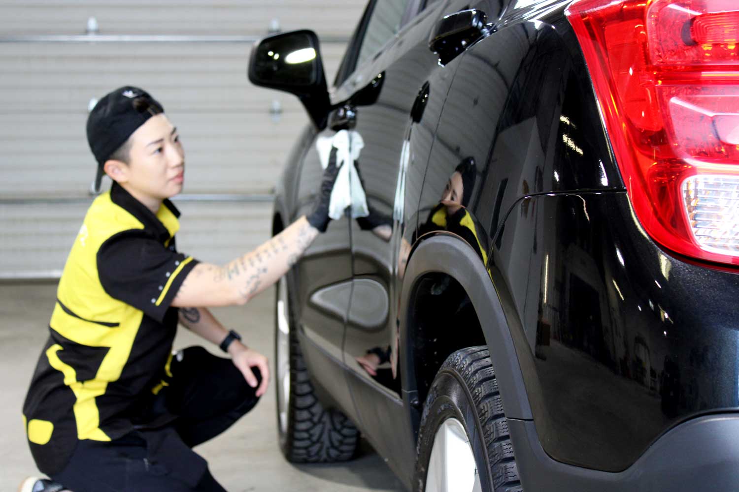 RestorFX Technician treating black vehicle side to complete shine at the Richmond center shop area