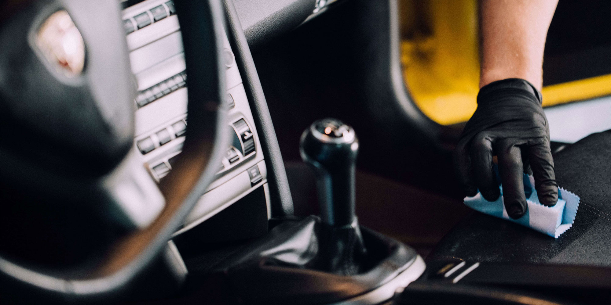 Un technicien <span  class='notranslate'>RestorFX</span> protégeant la console en cuir d'une voiture de sport jaune avec le produit <span  class='notranslate'><span  class='notranslate'>ClearFX</span> Interior</span>