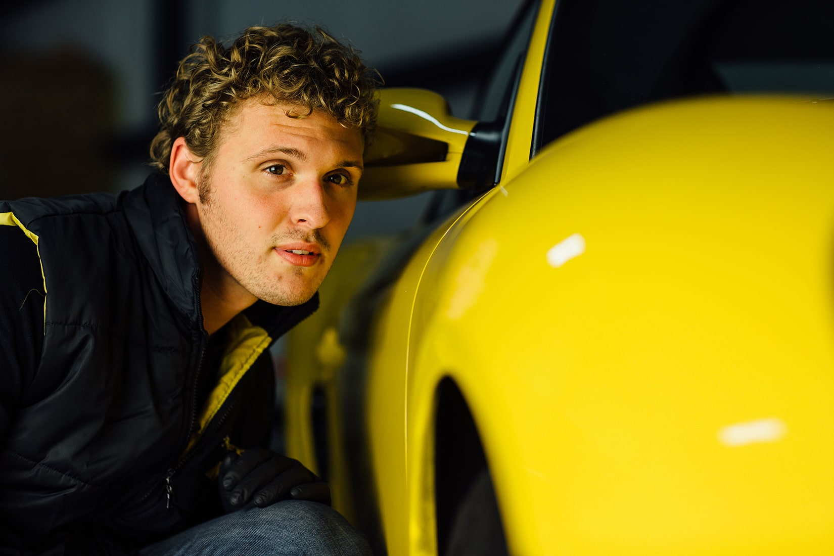A RestorFX technician visually inspecting the restored surface of a yellow sports car and checking the quality up close