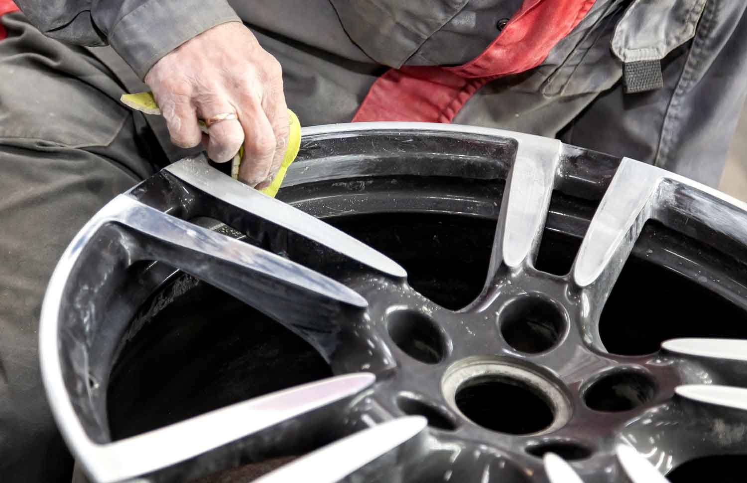 Technician preparing an aluminum wheel for subsequent painting using an abrasive material