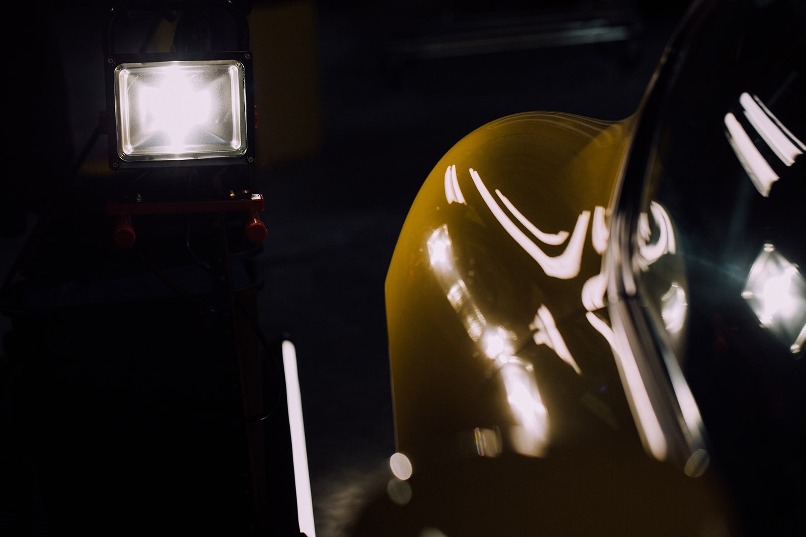 Un foco/luz de trabajo LED de alta intensidad dirigido a un automóvil deportivo amarillo para iluminación directa (sin filtrar)