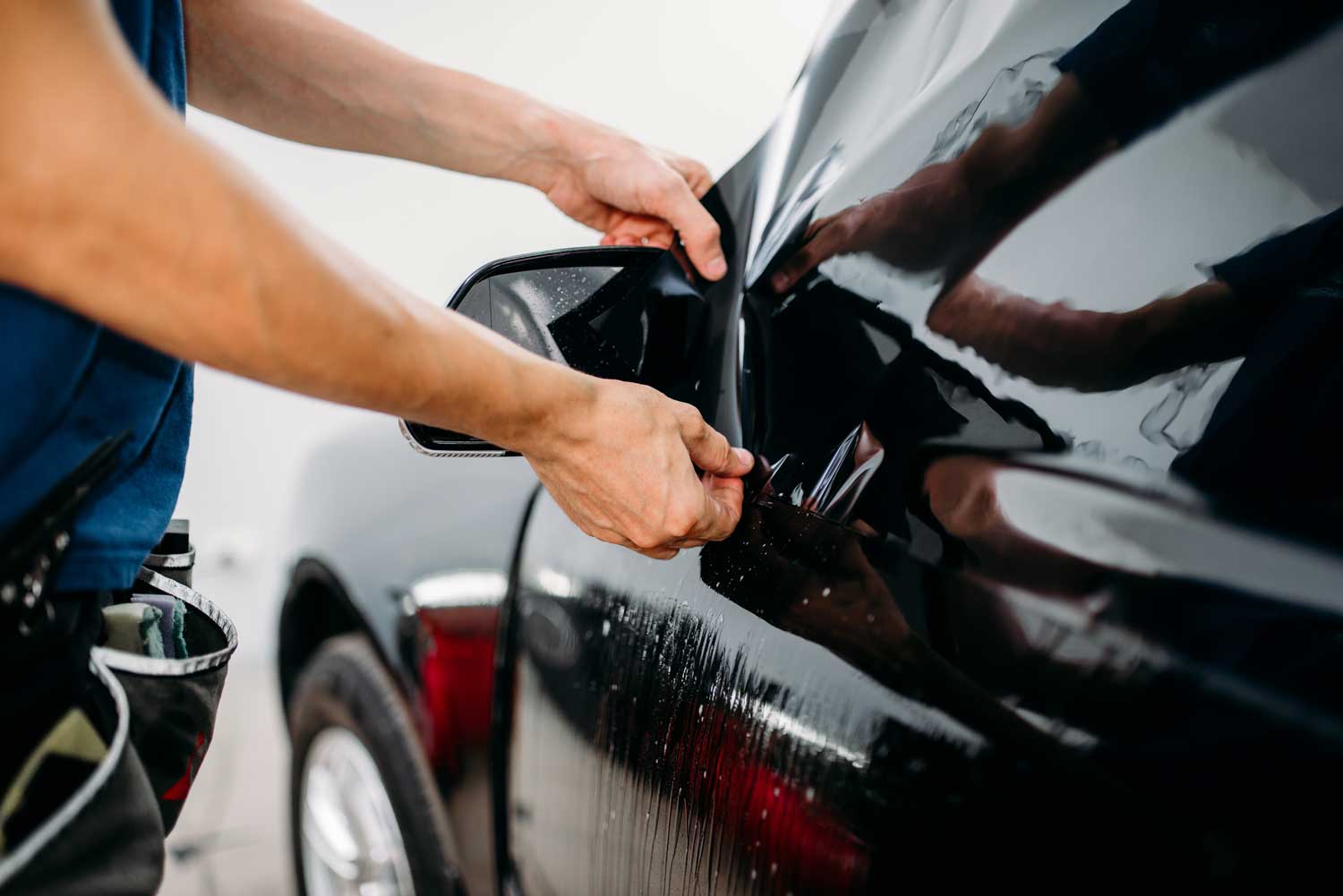 Technician applies tinted film to vehicle's windows