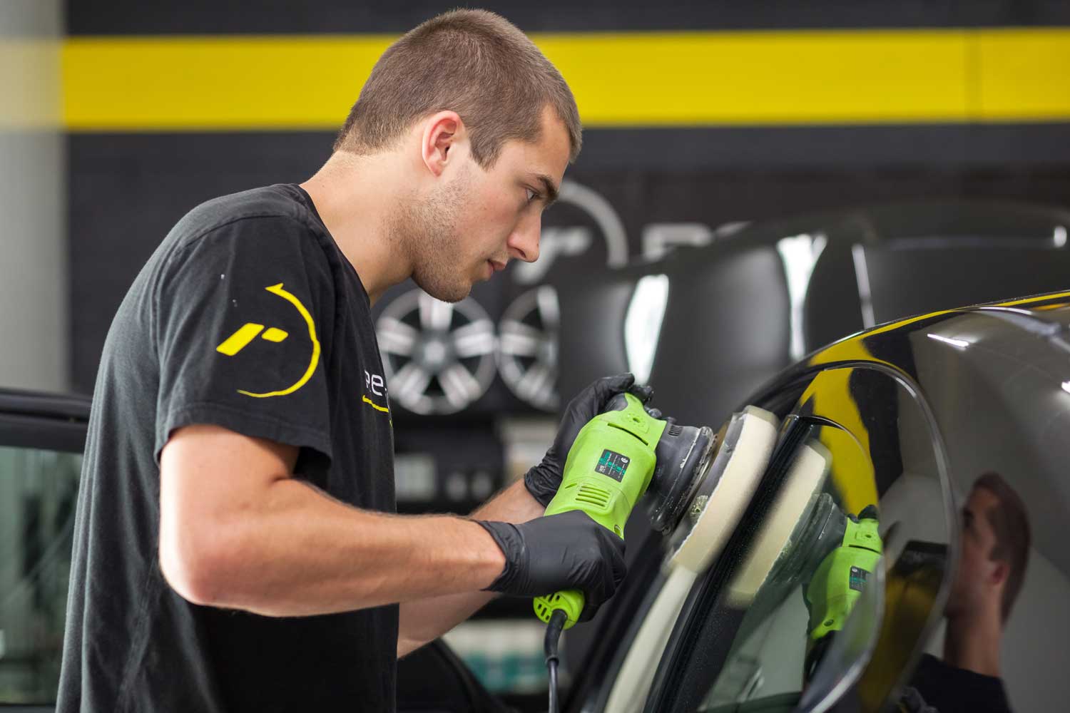 A RestorFX Technician does two-step polish and wax on black vehicle in shop area for great shine