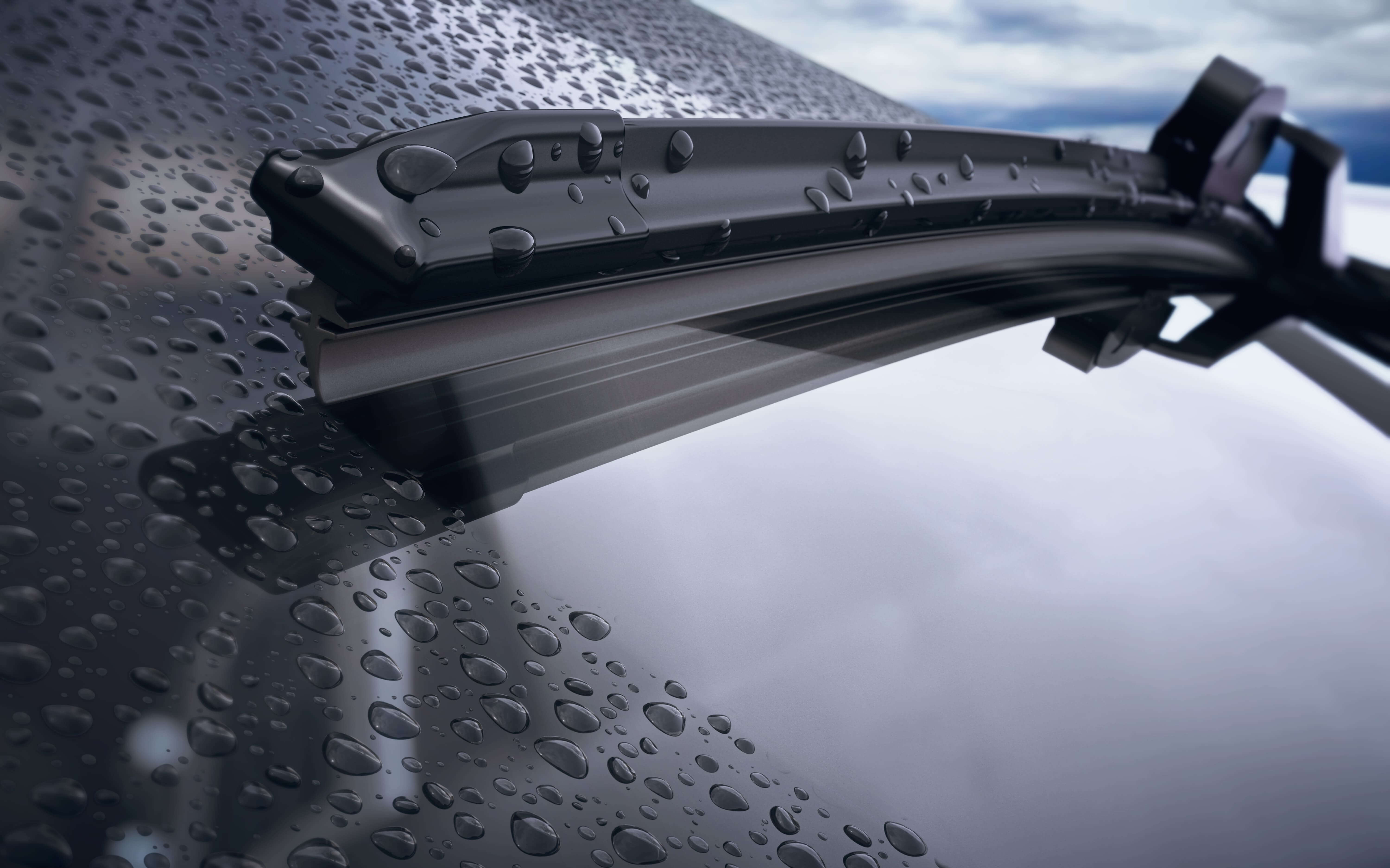 Klar, blank bilvindruta med regndroppar och reflektion av himlen och ett ramlöst torkarblad
